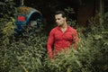 A brunette man of model appearance in a red shirt next to an abandoned telephone booth Royalty Free Stock Photo