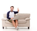 Brunette man smiling sitting on couch with laptop.