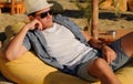 Brunette man wearing straw hat sleepng in a beach cafe.