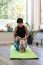 Brunette middle aged woman doing yoga meditation on exercise mat with dog at home, mental health, mental balance, time