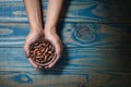 Brunette model holding ceramic pot with baru chestnut, blue wooden background