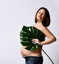 Pregnant model in jeans, naked to waist. Kissing you, covering chest by leaf, touching tummy, posing sideways isolated on white Royalty Free Stock Photo