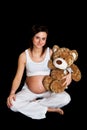 Brunette pregnant woman with teddy bear on black Royalty Free Stock Photo