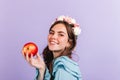 Brunette with roses in her hair is holding red apple. Closeup portrait of girl in image of modern Snow White. Royalty Free Stock Photo