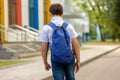 A brunette schoolboy in a white shirt, blue tie and blue backpack goes to school Royalty Free Stock Photo