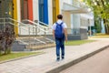 A brunette schoolboy in a white shirt, blue tie and blue backpack goes to school with colorful windows. Royalty Free Stock Photo