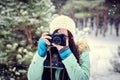 Brunette smiling girl photographed on an old vintage camera in winter forest Royalty Free Stock Photo