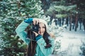 Brunette smiling girl photographed on an old vintage camera in winter forest Royalty Free Stock Photo