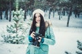 Brunette smiling girl photographed on an old vintage camera in winter forest Royalty Free Stock Photo