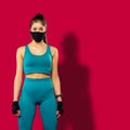 Brunette sportwoman wearing blue fitness clothing and black medical protective face mask training indoors. Fitness fit form,