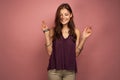 The brunette is standing on a pink background in a purple top, smiling looking down. Royalty Free Stock Photo