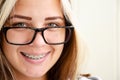 Brunette teen girl with glasses in dental braces. Beautiful caucasian young girl with green eyes looks at camera and smiles. Royalty Free Stock Photo