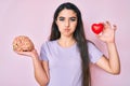 Brunette teenager girl holding brain and heart puffing cheeks with funny face Royalty Free Stock Photo