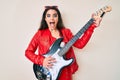 Brunette teenager girl playing electric guitar celebrating crazy and amazed for success with open eyes screaming excited Royalty Free Stock Photo