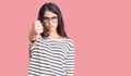 Brunette teenager girl wearing casual clothes and glasses looking unhappy and angry showing rejection and negative with thumbs Royalty Free Stock Photo