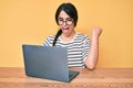 Brunette teenager girl working using computer laptop screaming proud, celebrating victory and success very excited with raised Royalty Free Stock Photo