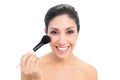 Brunette using a powder brush and smiling Royalty Free Stock Photo