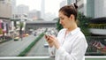 Brunette in white types on smartphone on bridge over street