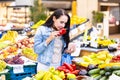 Brunette wman smells red pepper from colorful selection of fruit and vegetables in the farmers market