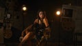 Brunette woman in black dress sitting on directors chair behind the scene, holding megaphone and looking at the camera. Royalty Free Stock Photo