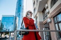 A brunette woman in branded clothes orders a taxi through a smartphone app.