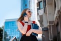 A brunette woman in branded clothes orders a taxi through a smartphone app.