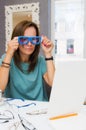 Brunette woman choosing and buying eyeglasses in optician salon or shop