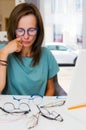 Brunette woman choosing and buying eyeglasses in optician salon or shop