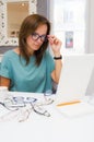 Brunette woman choosing and buying eyeglasses in optician salon or shop