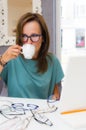 Brunette woman choosing and buying eyeglasses in optician salon or shop