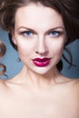 Brunette woman with creative make up violet eye shadows full red lips, blue eyes and curly hair with her hand on her face Royalty Free Stock Photo