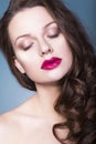 Brunette woman with creative make up violet eye shadows full red lips, blue eyes and curly hair with her hand on her face Royalty Free Stock Photo