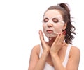 Brunette woman doing facial mask sheet. Beauty and Skin Care Concept. Girl applying mask to her face, studio shot Royalty Free Stock Photo