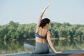 Brunette woman doing yoga outdoors in a beautiful spot on a riverside