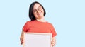 Brunette woman with down syndrome holding empty white chalkboard looking positive and happy standing and smiling with a confident Royalty Free Stock Photo