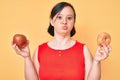 Brunette woman with down syndrome holding red apple and donut sitting looking at the camera blowing a kiss being lovely and sexy Royalty Free Stock Photo