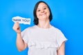 Brunette woman with down syndrome holding thank you paper looking positive and happy standing and smiling with a confident smile Royalty Free Stock Photo