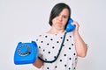 Brunette woman with down syndrome holding vintage telephone depressed and worry for distress, crying angry and afraid