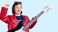 Brunette woman with down syndrome playing electric guitar surprised with an idea or question pointing finger with happy face,