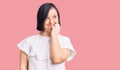 Brunette woman with down syndrome wearing casual white tshirt looking stressed and nervous with hands on mouth biting nails Royalty Free Stock Photo