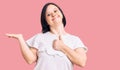 Brunette woman with down syndrome wearing casual white tshirt showing palm hand and doing ok gesture with thumbs up, smiling happy Royalty Free Stock Photo