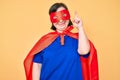 Brunette woman with down syndrome wearing super hero costume pointing finger up with successful idea