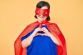 Brunette woman with down syndrome wearing super hero costume smiling in love showing heart symbol and shape with hands Royalty Free Stock Photo