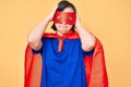 Brunette woman with down syndrome wearing super hero costume suffering from headache desperate and stressed because pain and