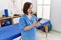 Brunette woman with down syndrome working using smartphone at physiotherapy clinic Royalty Free Stock Photo