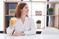 Brunette woman drinking glass of orange juice looking to side, relax profile pose with natural face and confident smile Royalty Free Stock Photo