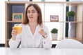 Brunette woman drinking glass of orange juice pointing fingers to camera with happy and funny face Royalty Free Stock Photo