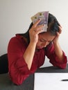 brunette woman with expression of despair and grabbing swedish money