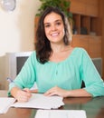Brunette woman filling papers at home