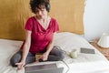 Brunette woman in front of her laptop sitting on the bed, listening and dancing with headphones some music, buying with credit